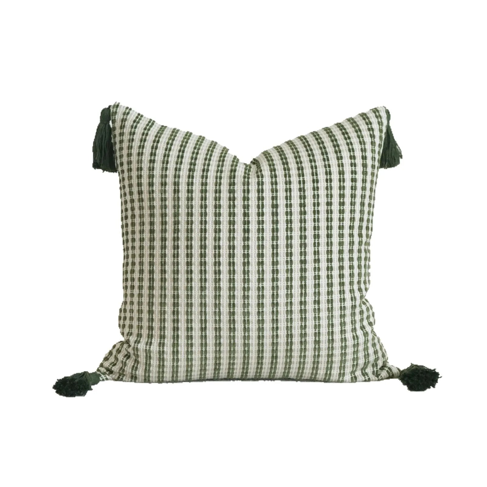 Green cotton and linen hotel pillow with tassel detail on a bed.