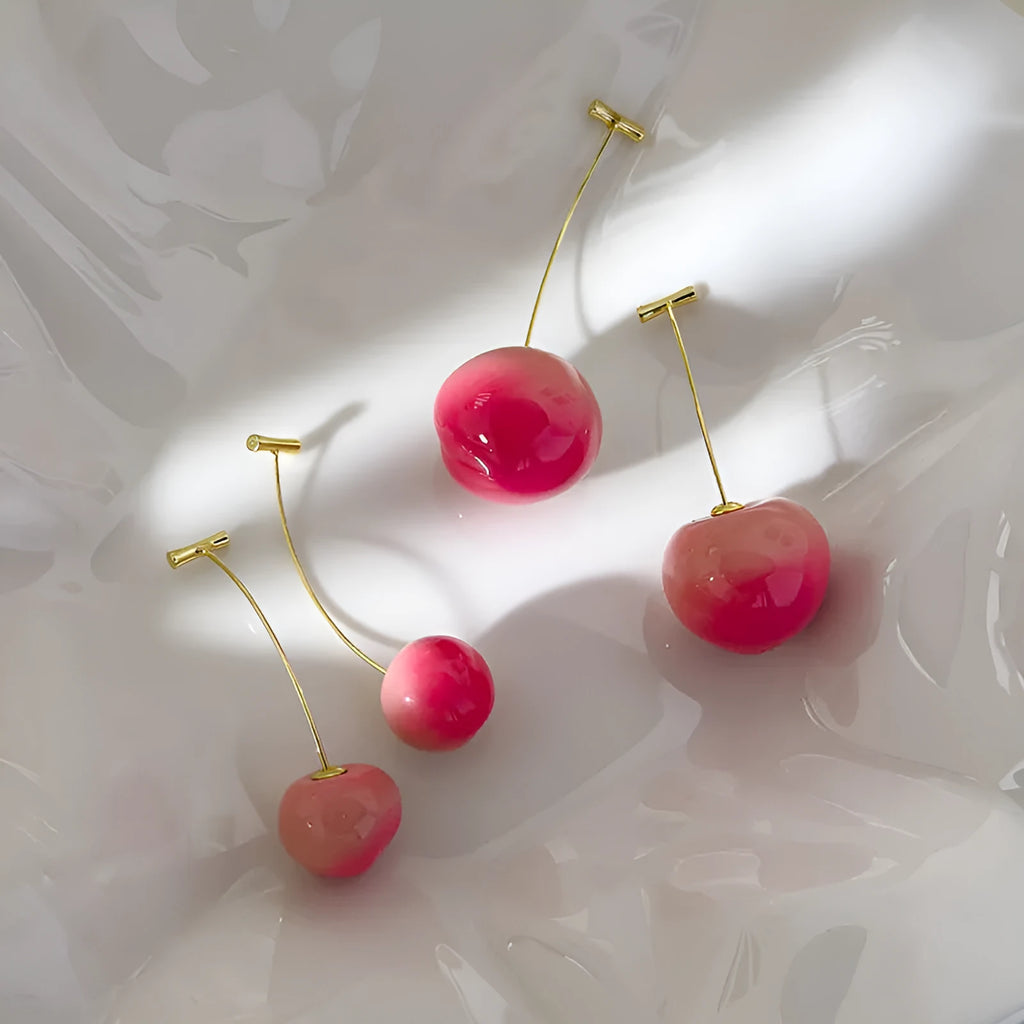 A pair of peach-shaped acrylic earrings in orange and green, shown in small and large size variants.
