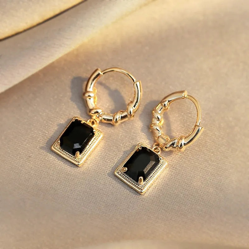 A pair of geometric copper earrings with black zircon stones in a quadrilateral design.