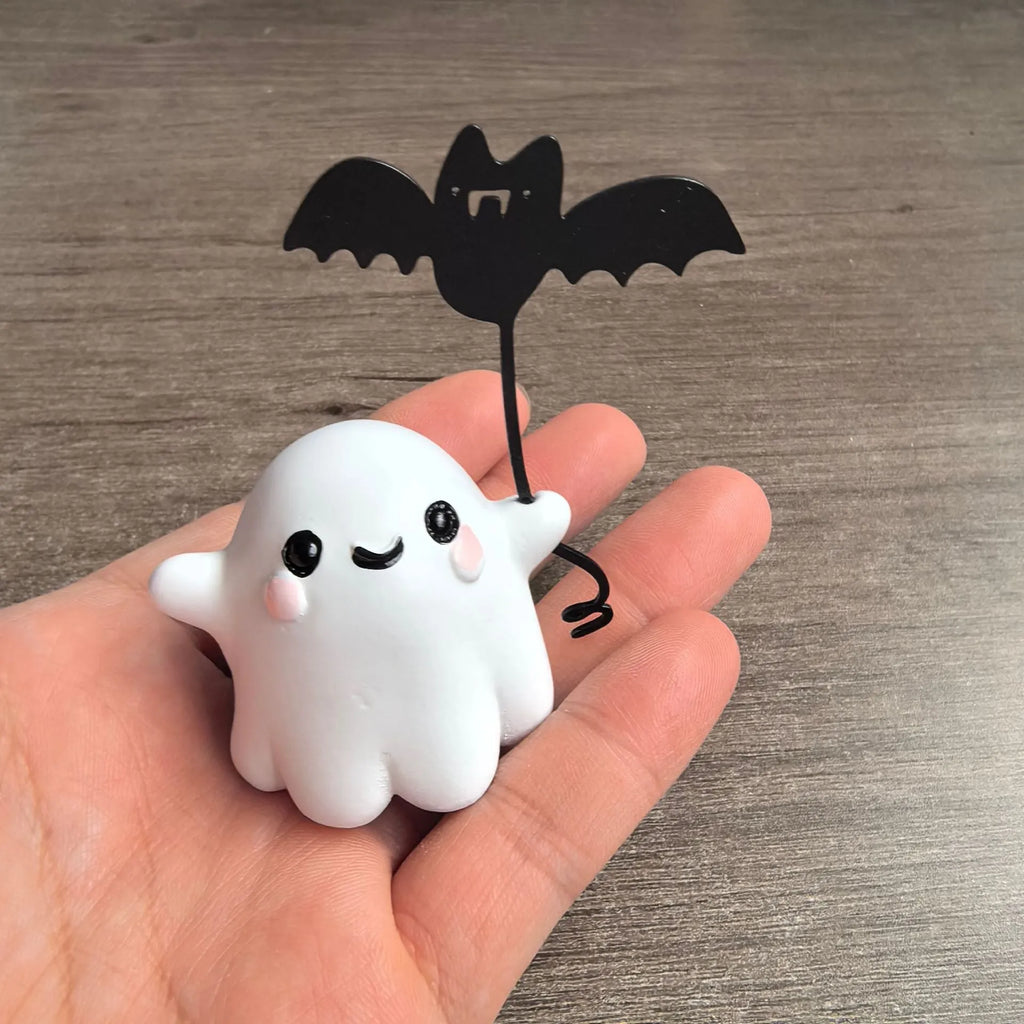 Small white resin statue of a ghost walking a spectral dog, a Halloween decoration.