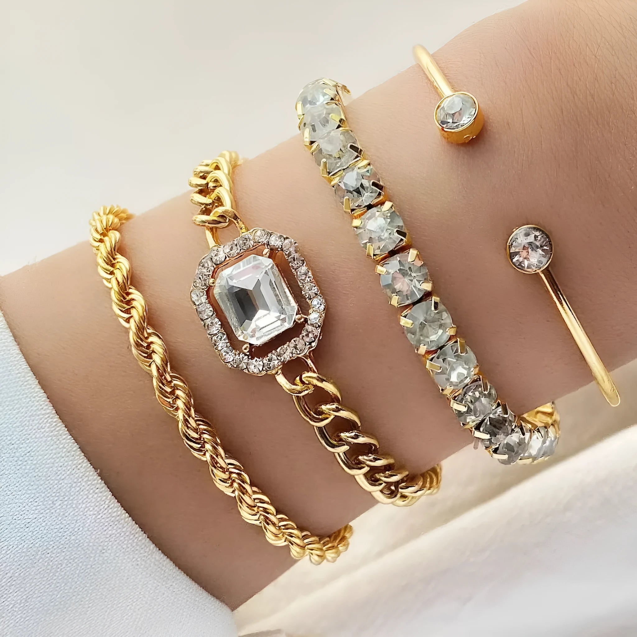 Four geometric bracelets with square diamond motifs on metal chains in gold colour