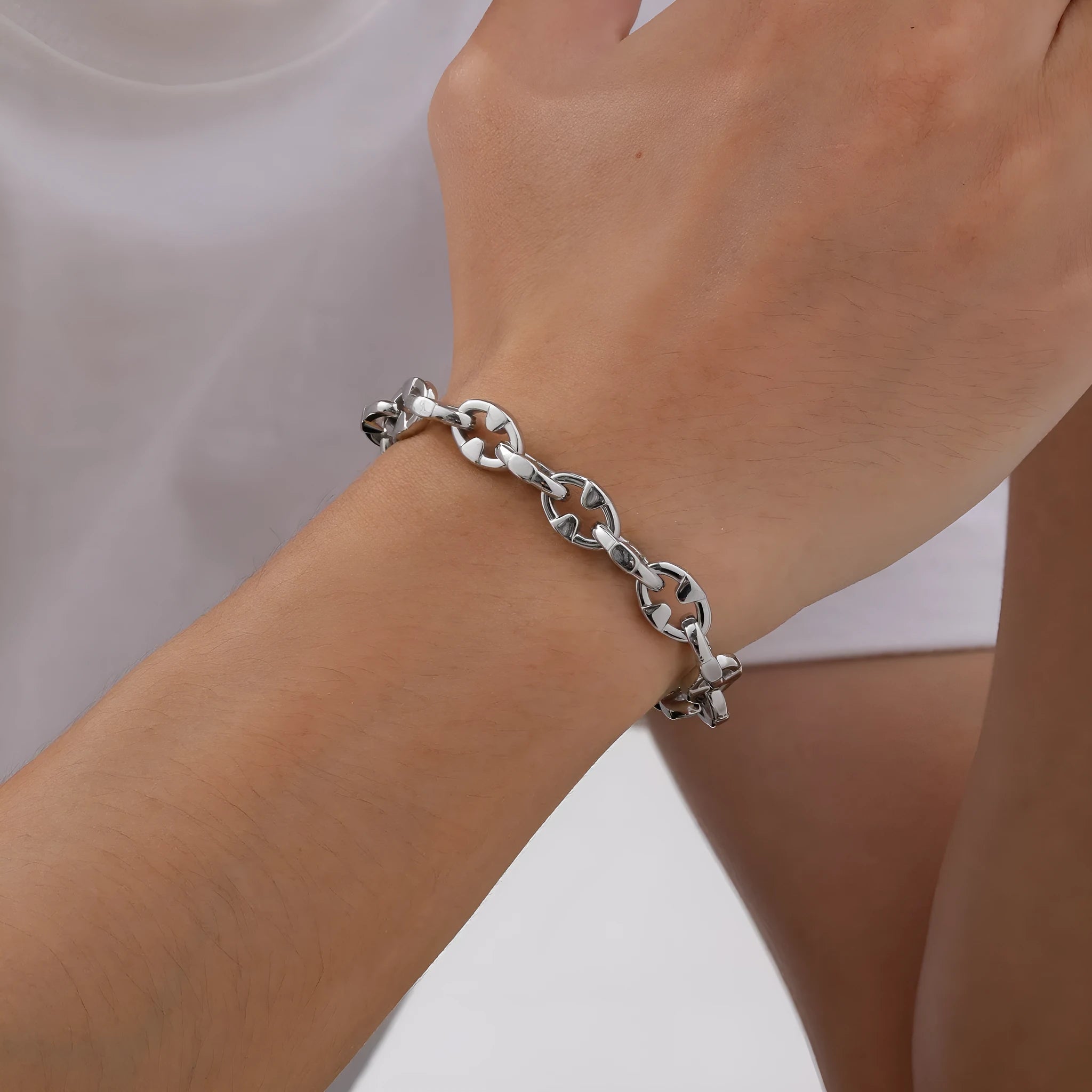 Close-up of a men's thick stainless steel geometric chain link bracelet on a wrist.