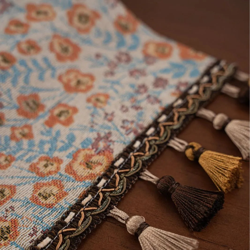 American-style beige jacquard table runner with floral pattern and long tassels on a dining table.