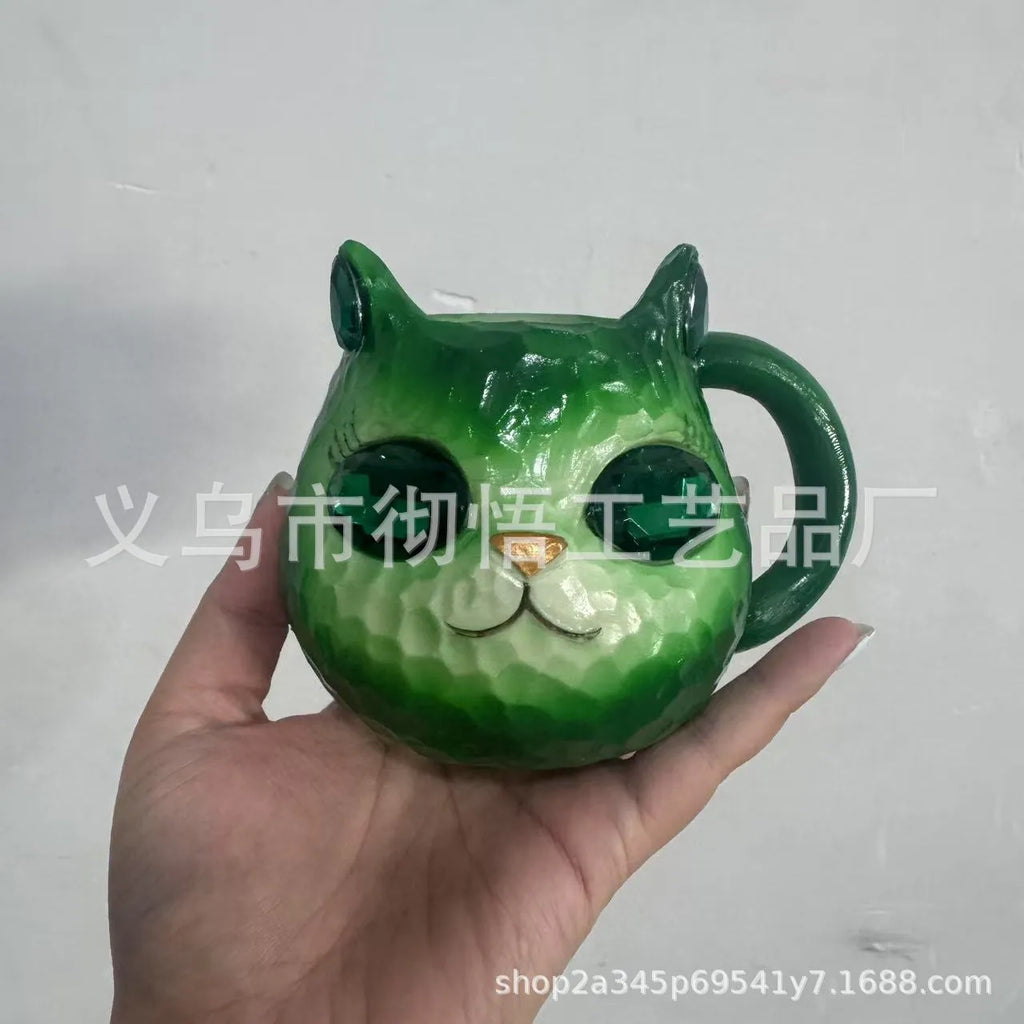 American-style resin ornament of a cat holding a crystal Earth globe in blue, green, pink, or purple.