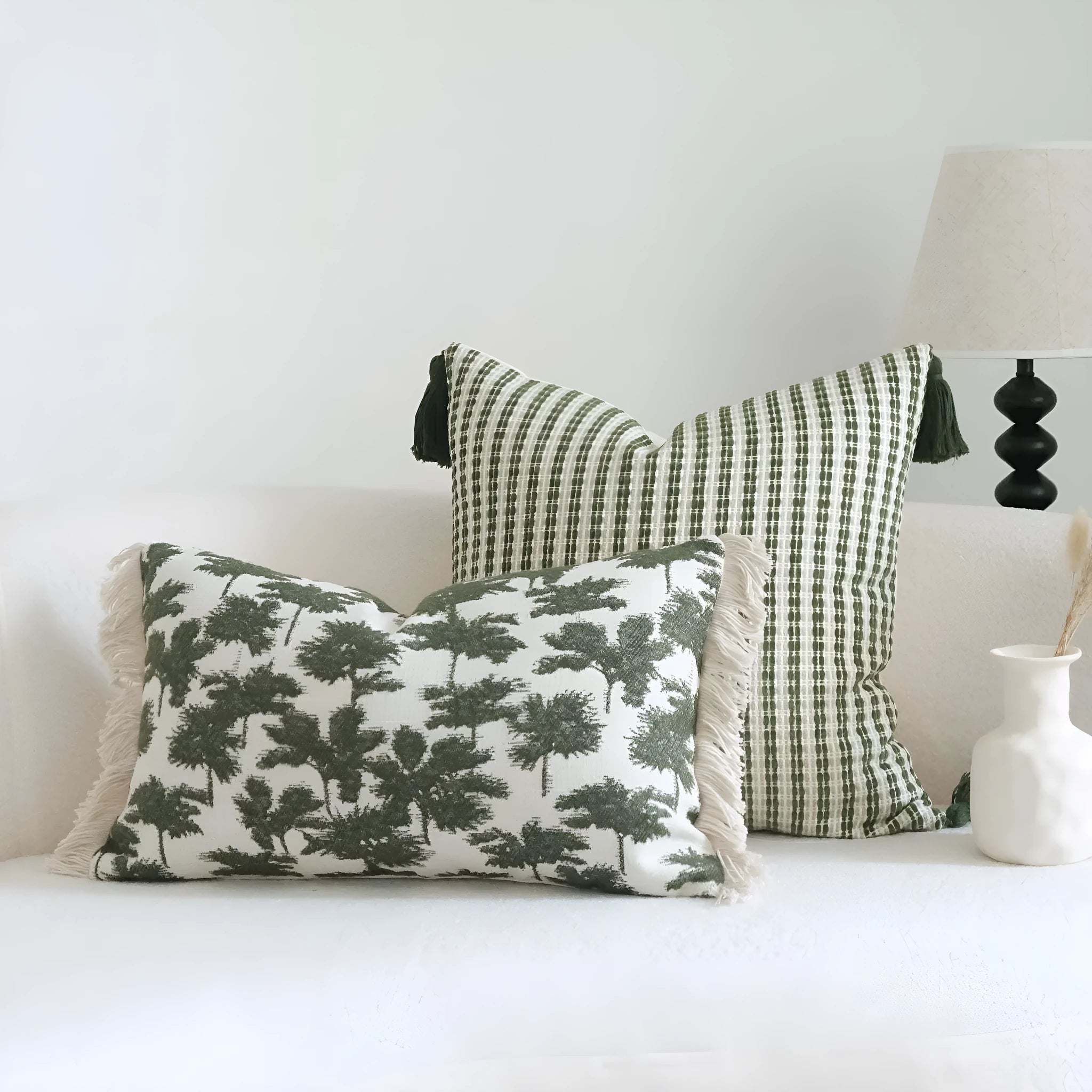 Green cotton and linen hotel pillow with tassel detail on a bed.