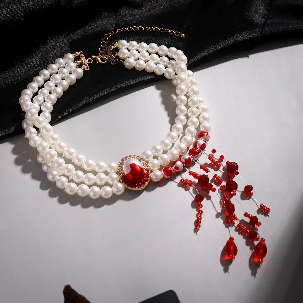 Halloween gothic jewellery set with pearl collar necklace, gold bracelet, and stud earrings on a dark background.