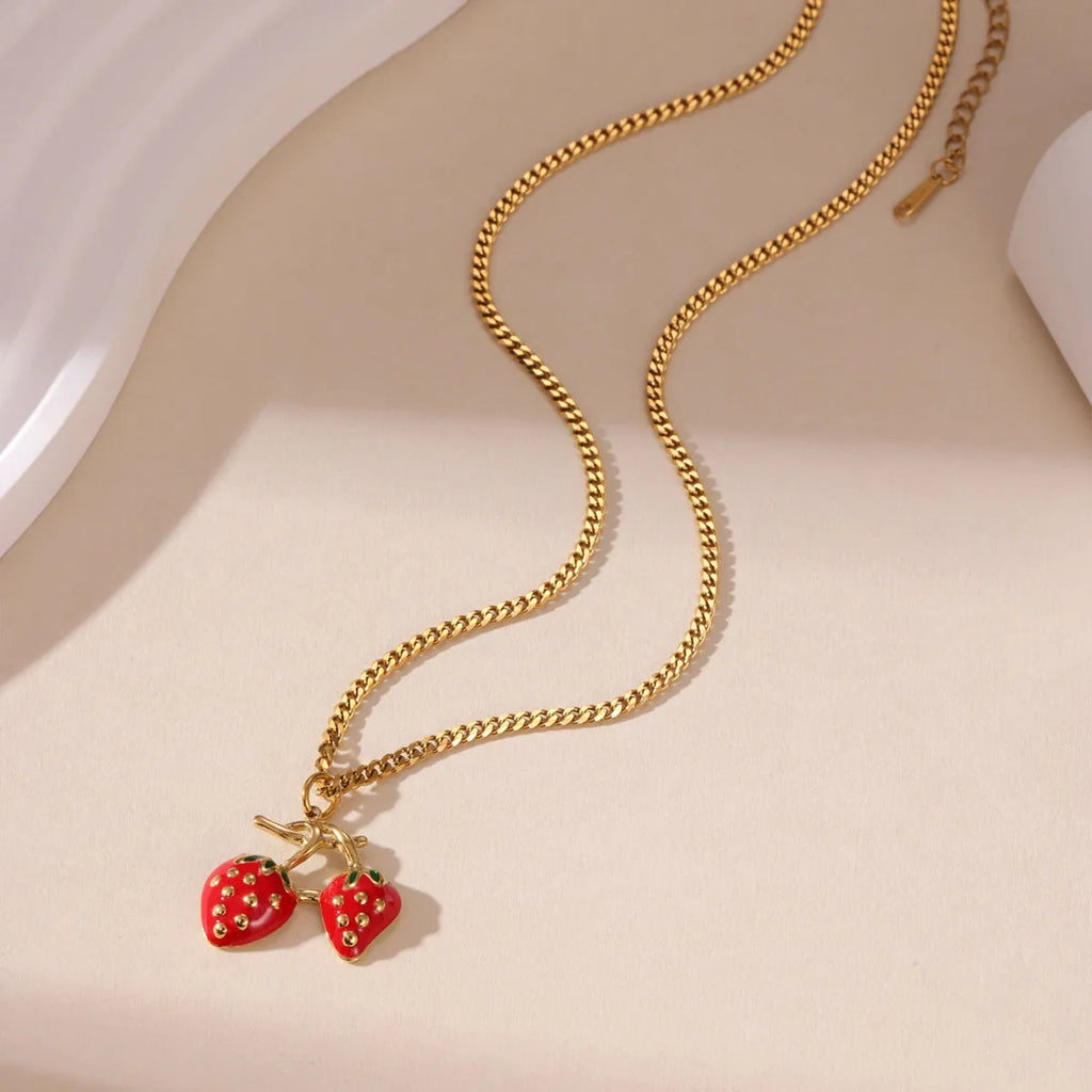 Close-up of a women's strawberry fruit pendant necklace with a detailed alloy charm on a stainless steel chain.