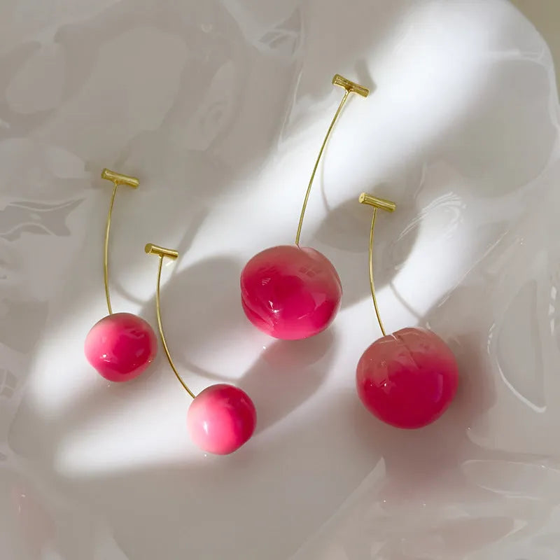 A pair of peach-shaped acrylic earrings in orange and green, shown in small and large size variants.