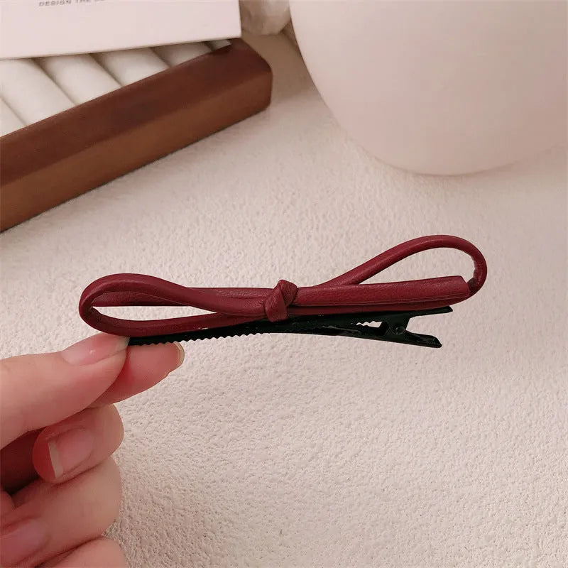 Wine red leather hair clip with a bow design, shown on a white background.