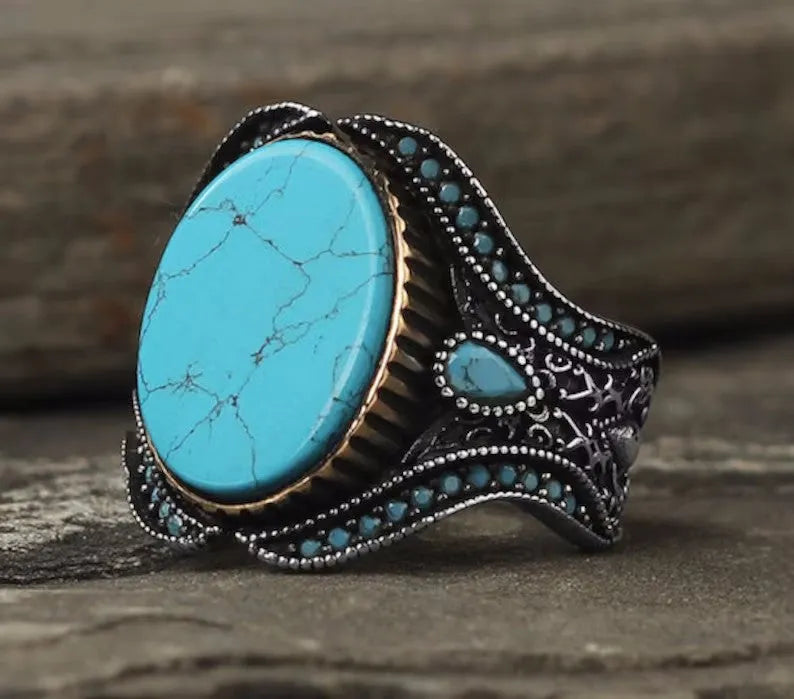 Men's antique silver alloy ring with a round band and a central turquoise stone on a finger.