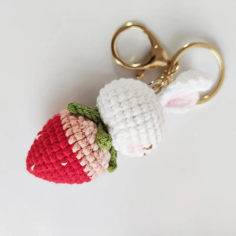 White hand-woven wire pendant of a cartoon rabbit with strawberry details, shown with an attachment key.