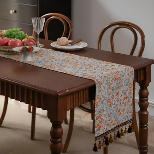 American-style beige jacquard table runner with floral pattern and long tassels on a dining table.