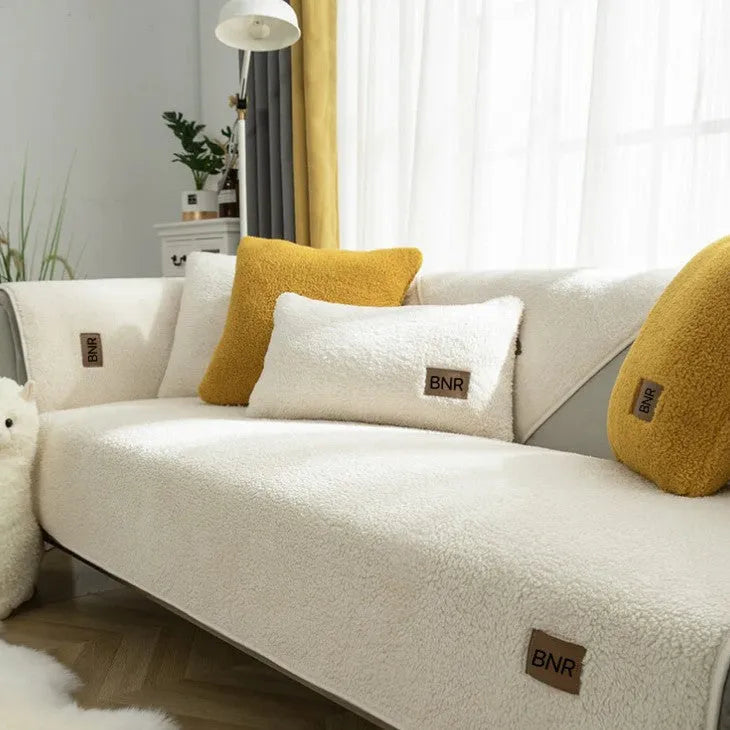 Solid colour lambswool sofa cover draped over a sofa, showing simple style and cloth liner.