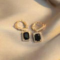 A pair of geometric copper earrings with black zircon stones in a quadrilateral design.