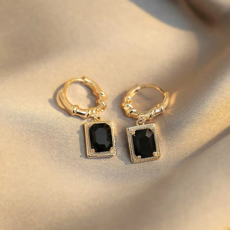 A pair of geometric copper earrings with black zircon stones in a quadrilateral design.
