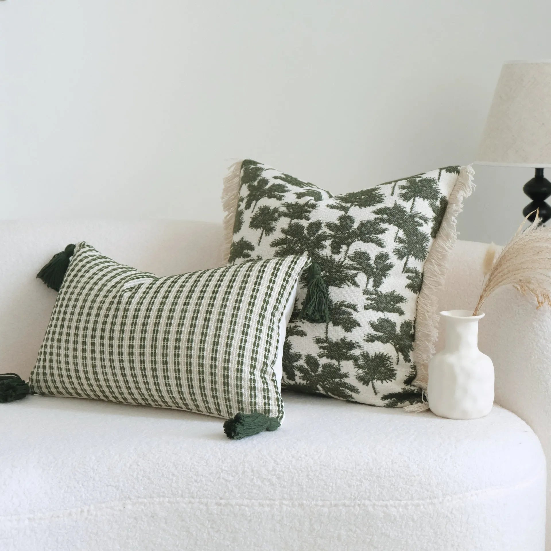 Green cotton and linen hotel pillow with tassel detail on a bed.