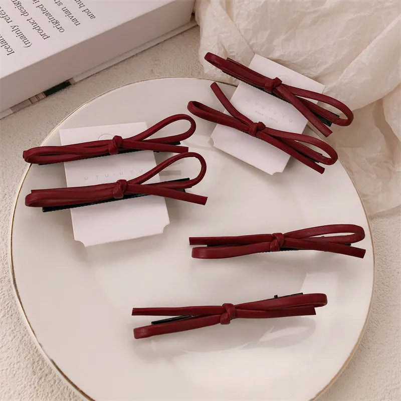 Wine red leather hair clip with a bow design, shown on a white background.