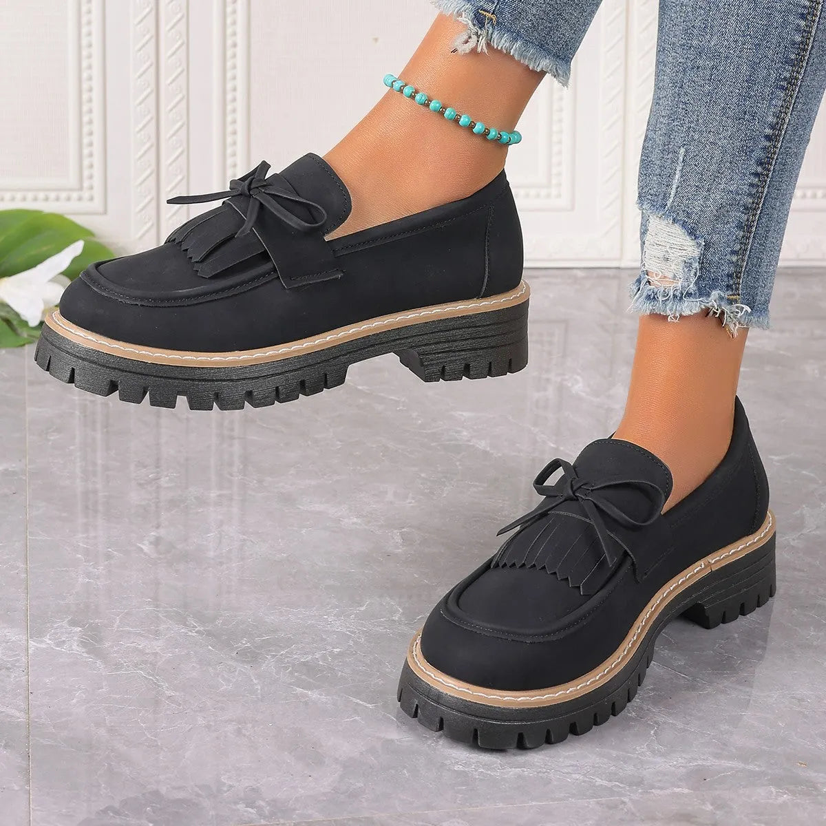 Black plus size women's loafers with a front bowknot and tassel on a chunky flat rubber sole.