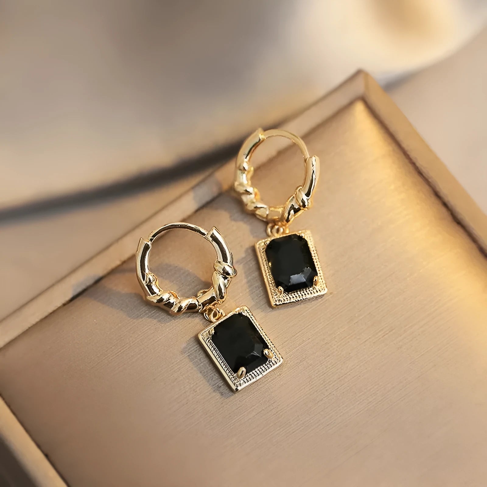 A pair of geometric copper earrings with black zircon stones in a quadrilateral design.