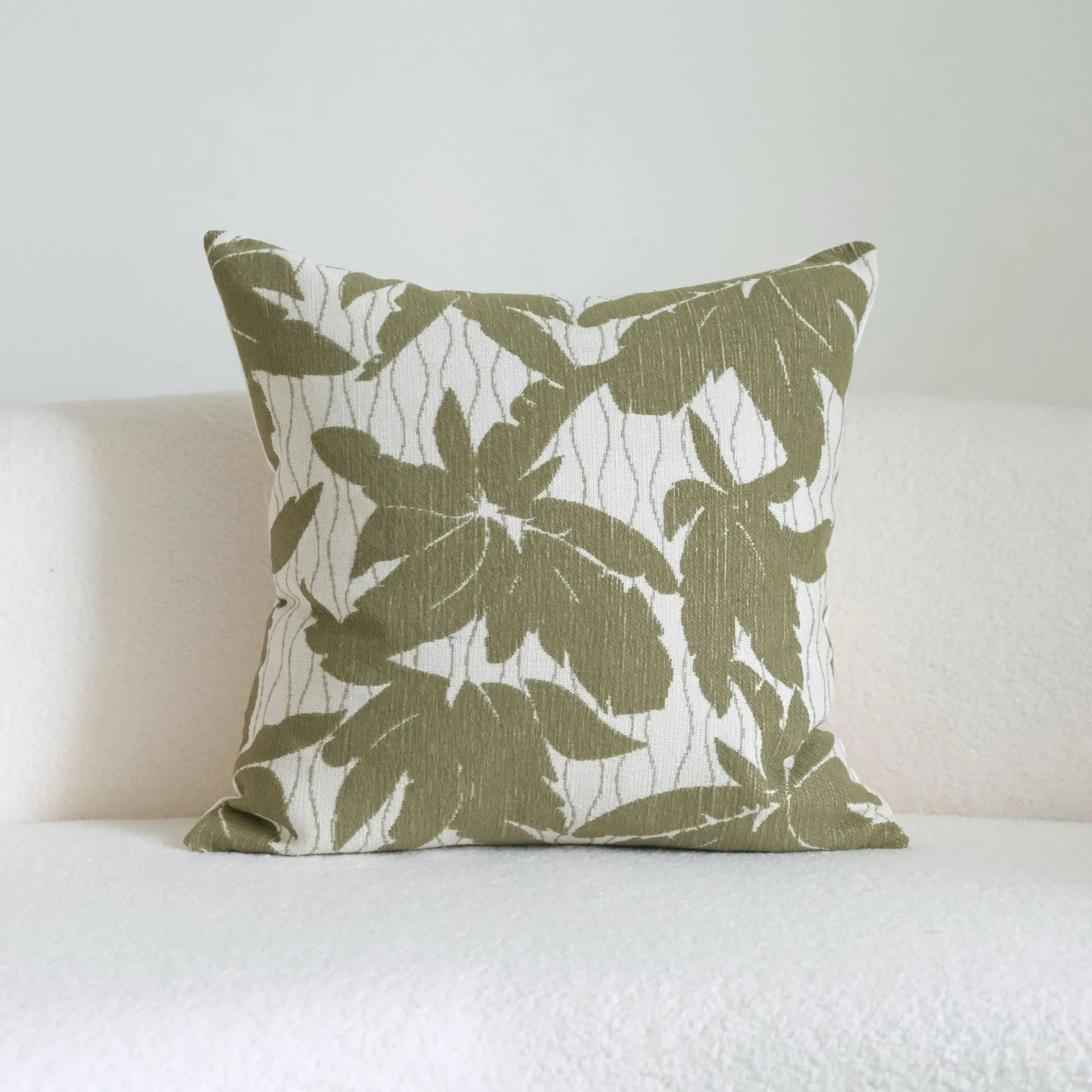 Green cotton and linen hotel pillow with tassel detail on a bed.