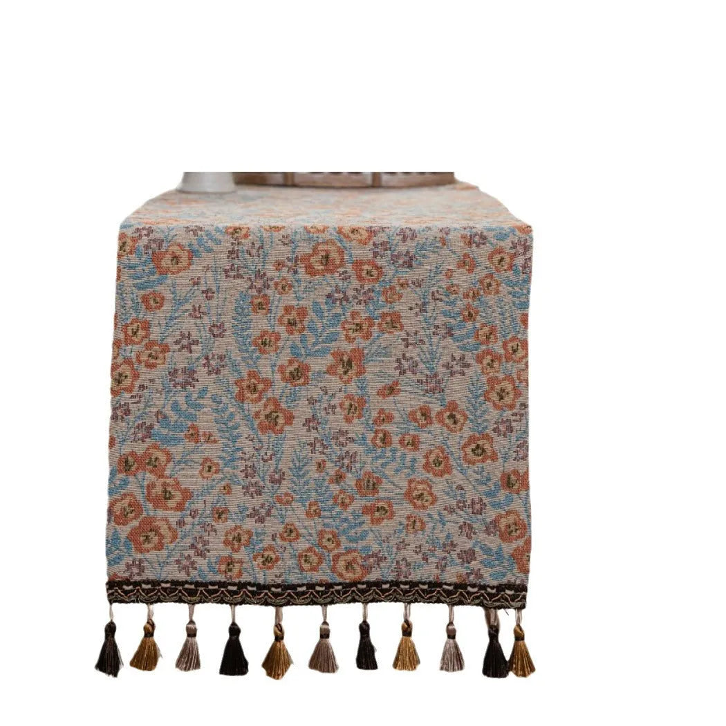 American-style beige jacquard table runner with floral pattern and long tassels on a dining table.