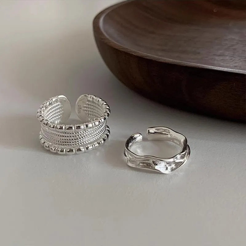 Copper alloy geometric ring with woven twisted design and adjustable opening.