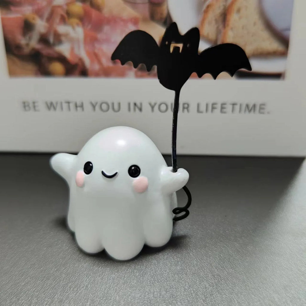 Small white resin statue of a ghost walking a spectral dog, a Halloween decoration.
