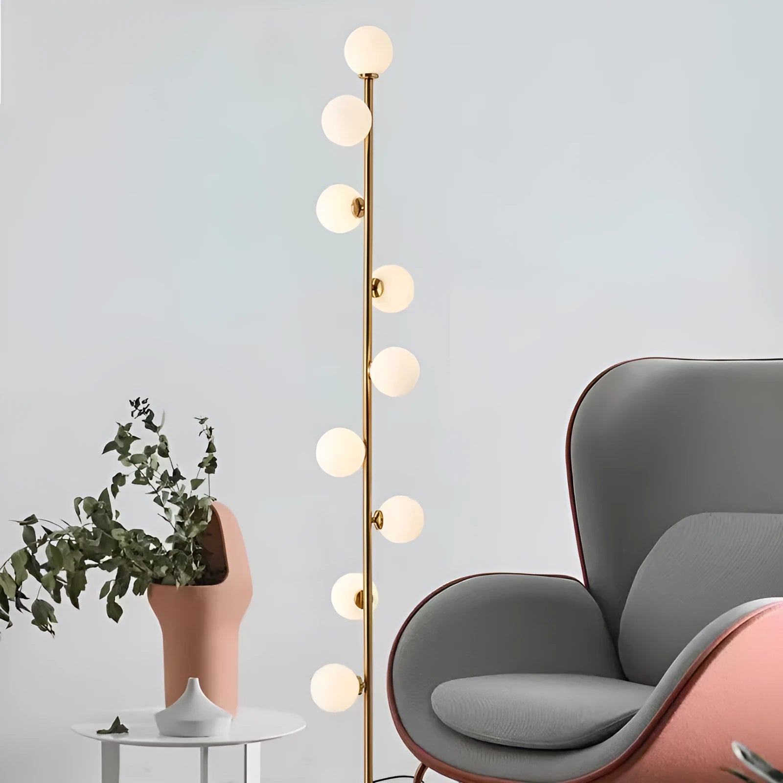 A tall modern minimalist floor lamp with a glass shade, wrought iron frame, and a grey marble base.