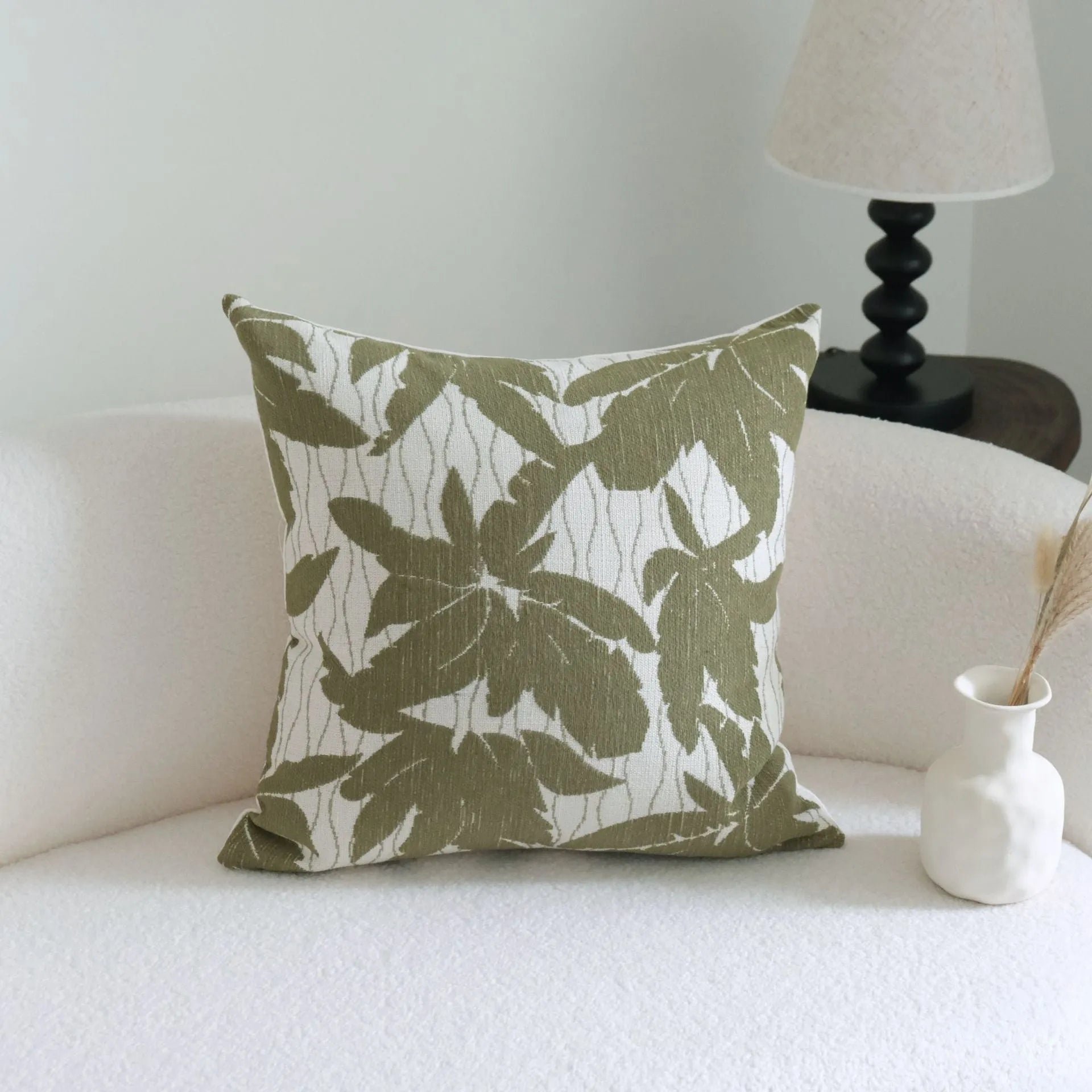 Green cotton and linen hotel pillow with tassel detail on a bed.