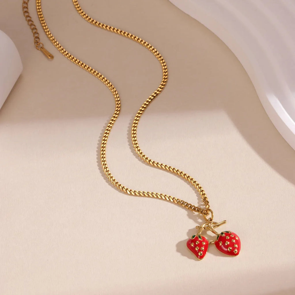 Close-up of a women's strawberry fruit pendant necklace with a detailed alloy charm on a stainless steel chain.