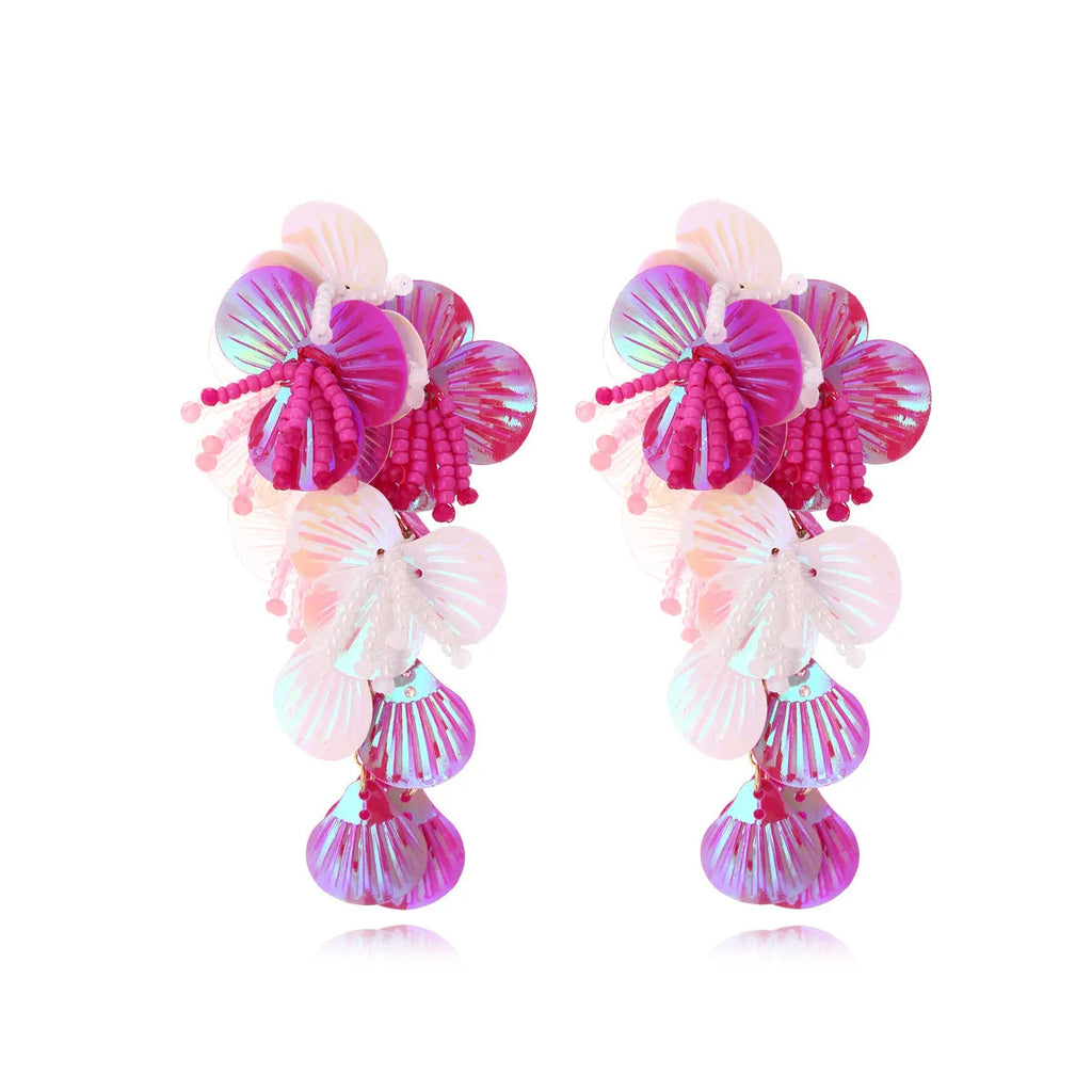 Handmade colourful flower and leaf earrings with string beads in rose and purple on a white background.