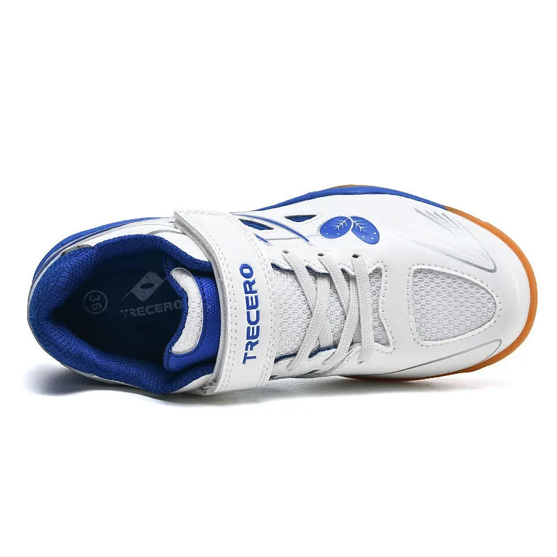 White and blue low-top badminton shoes with a ribbed sole and round toe on a hard court surface.