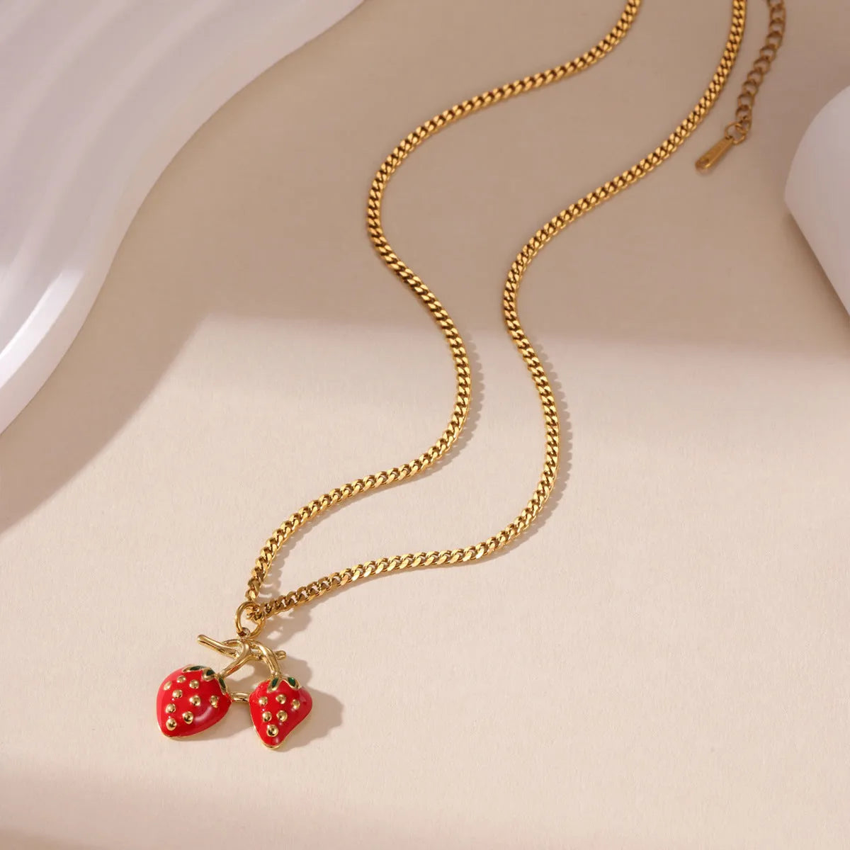 Close-up of a women's strawberry fruit pendant necklace with a detailed alloy charm on a stainless steel chain.