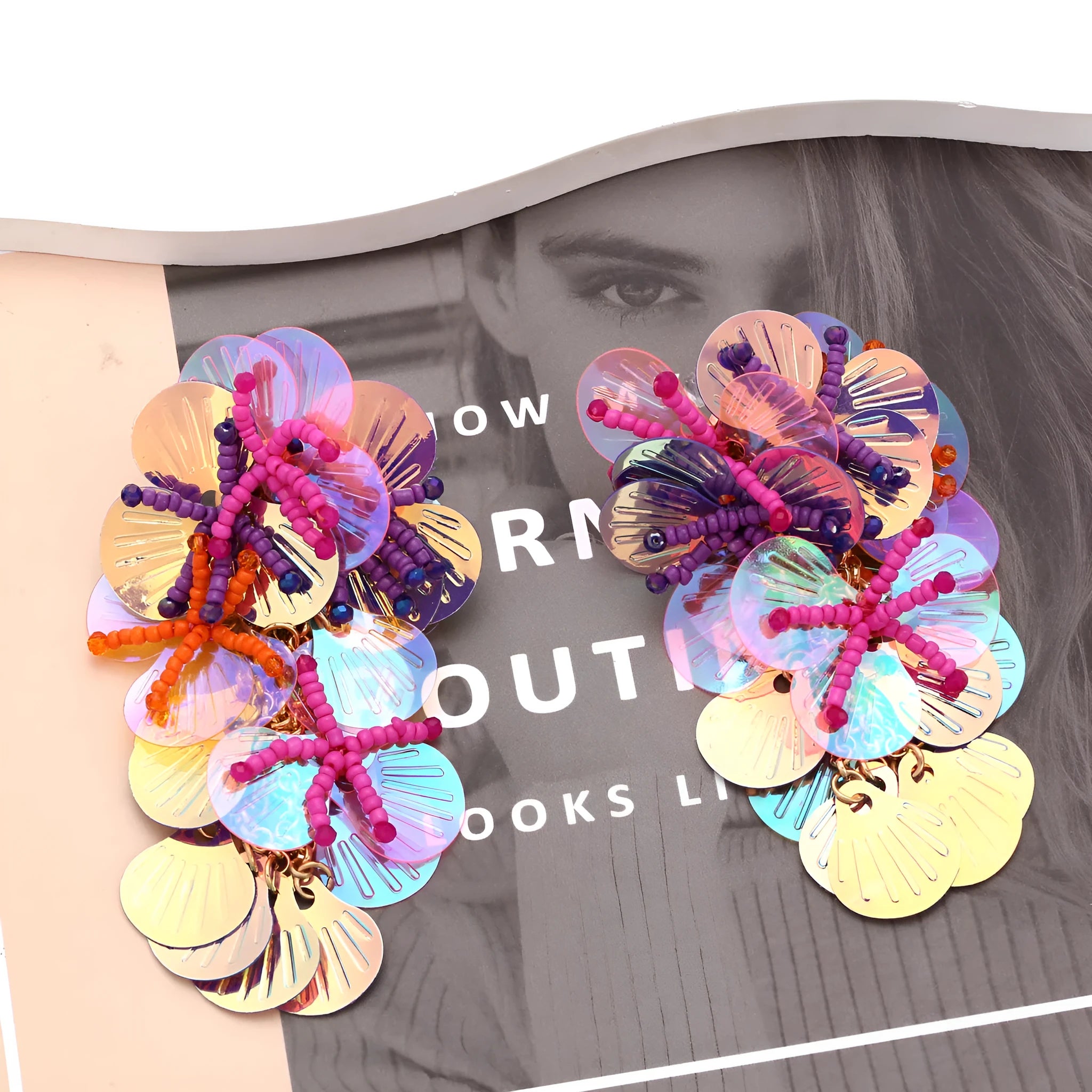 Handmade colourful flower and leaf earrings with string beads in rose and purple on a white background.