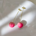 A pair of peach-shaped acrylic earrings in orange and green, shown in small and large size variants.