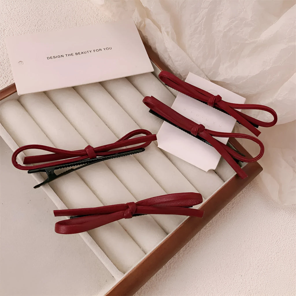 Wine red leather hair clip with a bow design, shown on a white background.