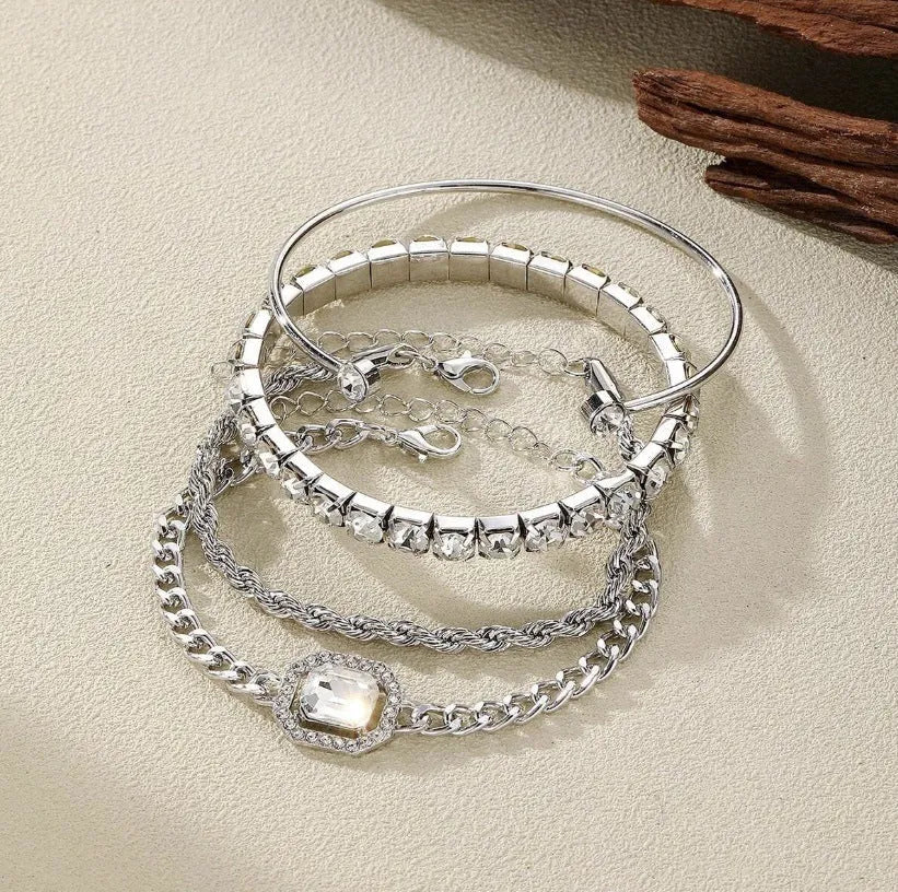 Four geometric bracelets with square diamond motifs on metal chains in gold colour