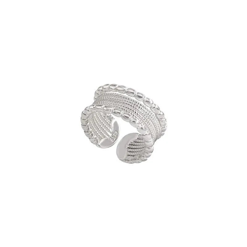 Copper alloy geometric ring with woven twisted design and adjustable opening.