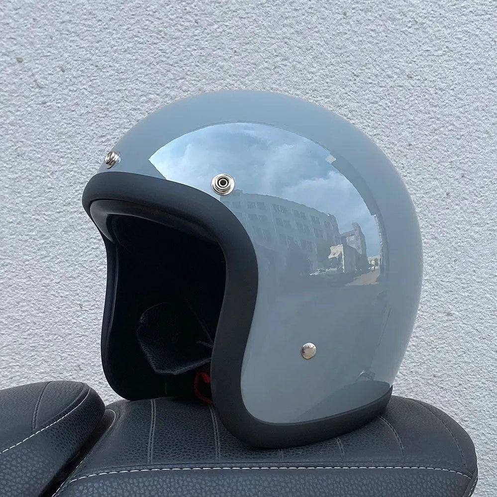 Retro-style open face motorcycle helmet in fibreglass, shown in a selection of colours including cement grey and matte black.