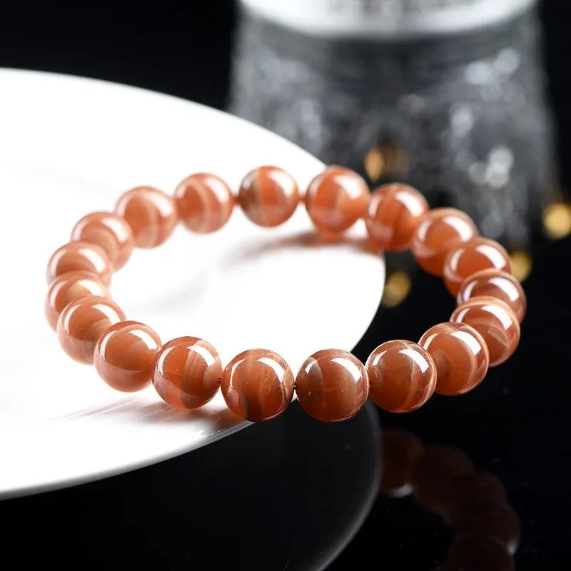 Natural old mine rhodochrosite bracelet with geometric beads and Ruyi symbols on a wrist.