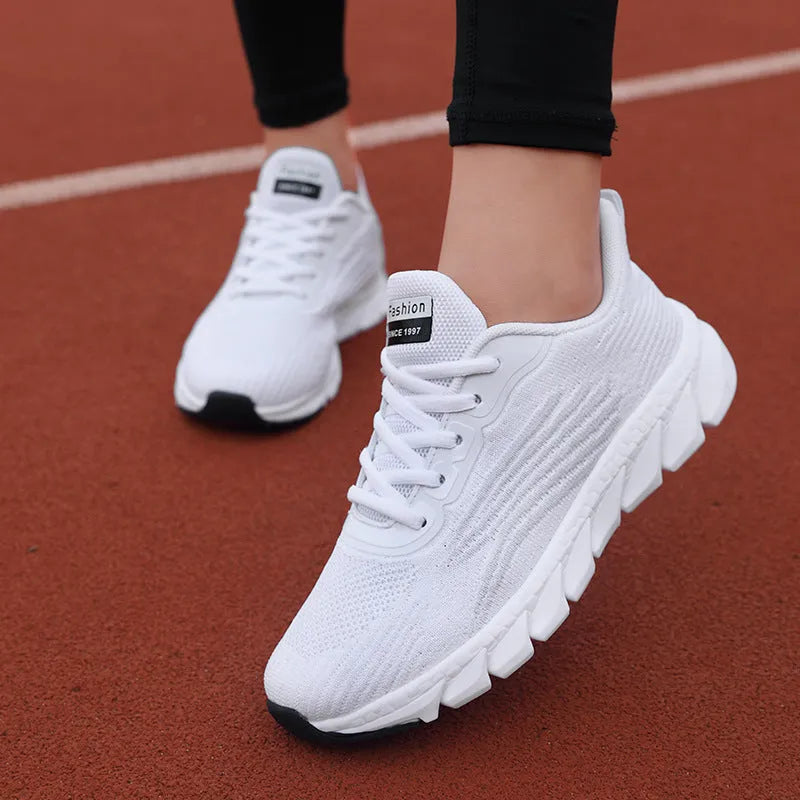 Low-top black and white running sneakers with cross-strap detail and a round toe on a flat MD sole.
