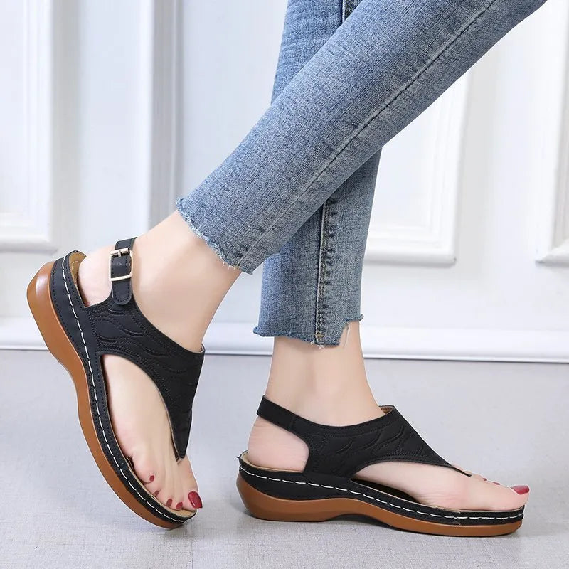 Women's black wedge heel sandals with an adjustable buckle back strap on a plain background.