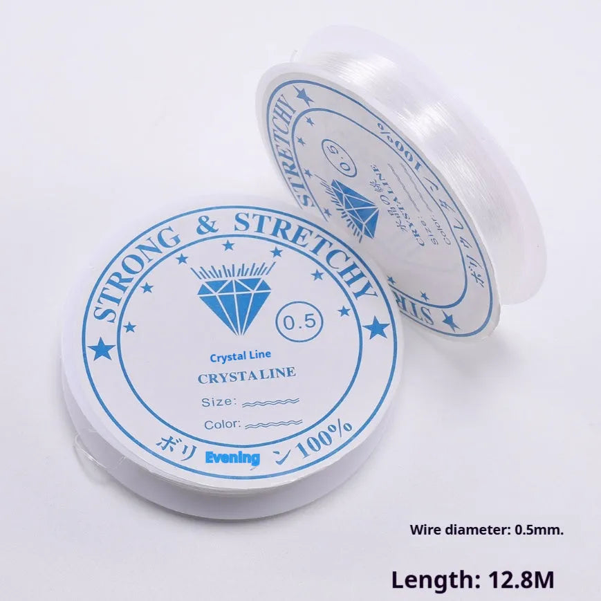 Spool of transparent white elastic cord for DIY jewellery making on a craft table.
