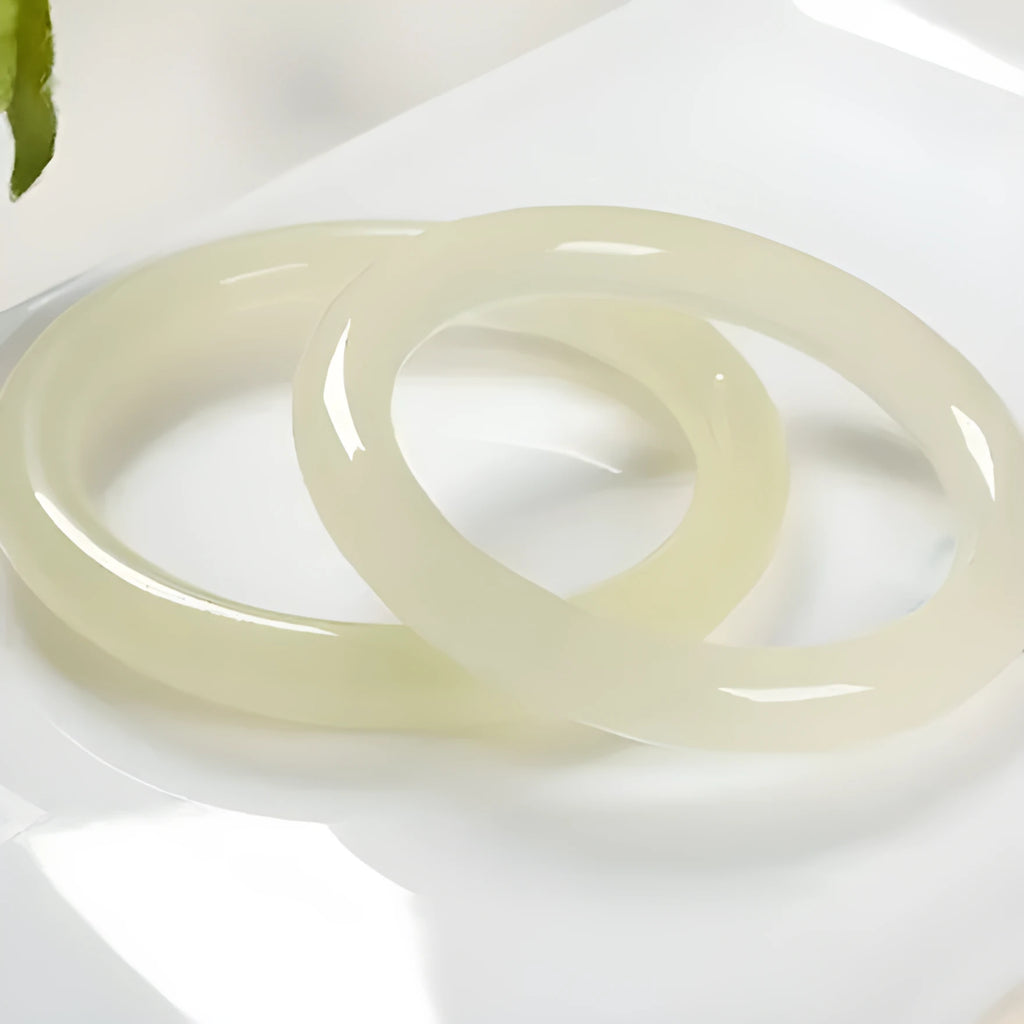 Close-up of a smooth, ice-like silk jade round bar bracelet on a wrist.
