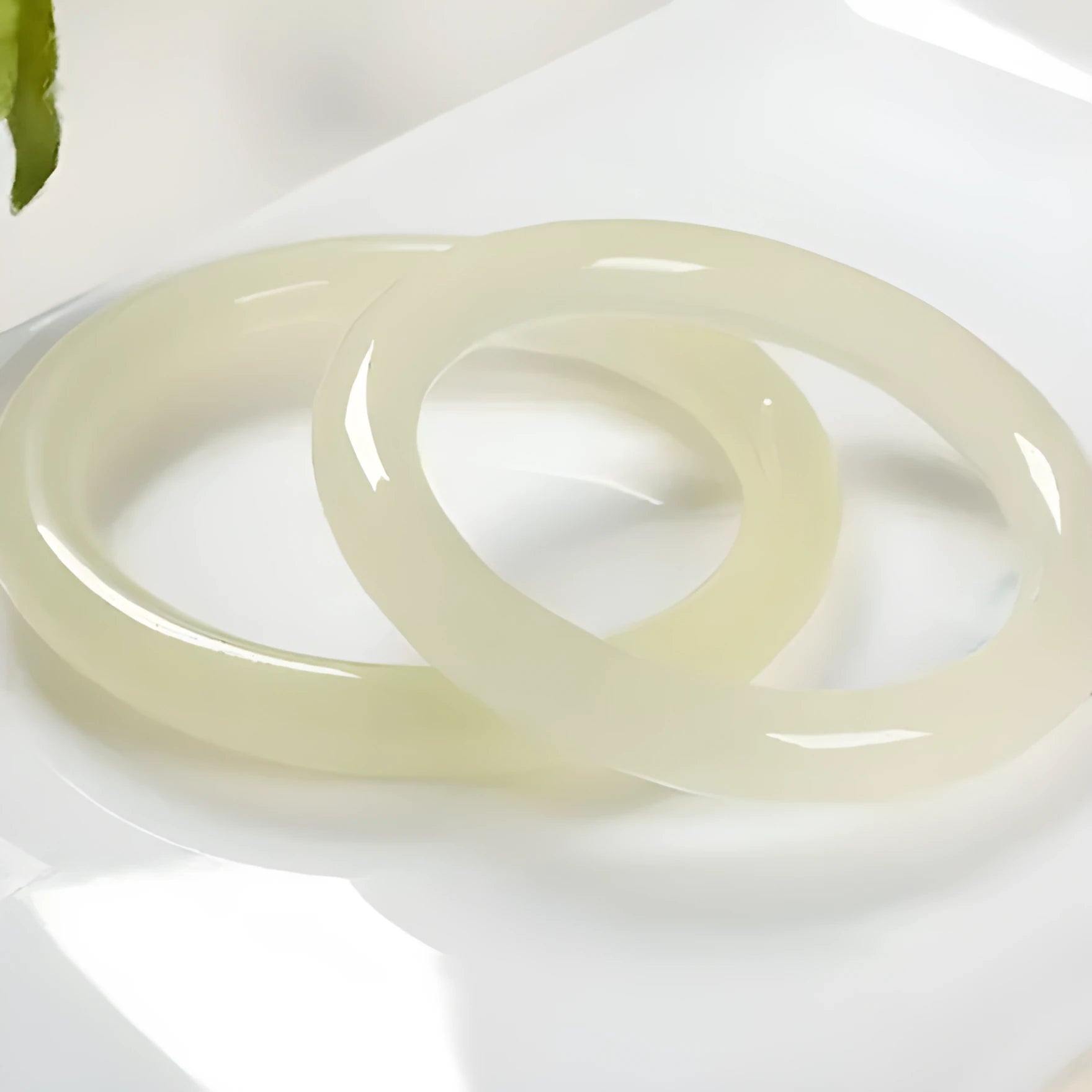 Close-up of a smooth, ice-like silk jade round bar bracelet on a wrist.