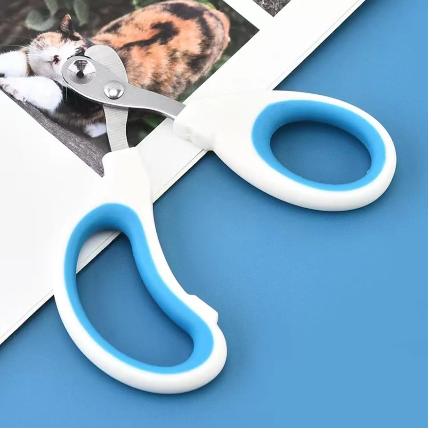 Blue cat nail clippers with a circular cutting hole and cushioned handles on a white surface.