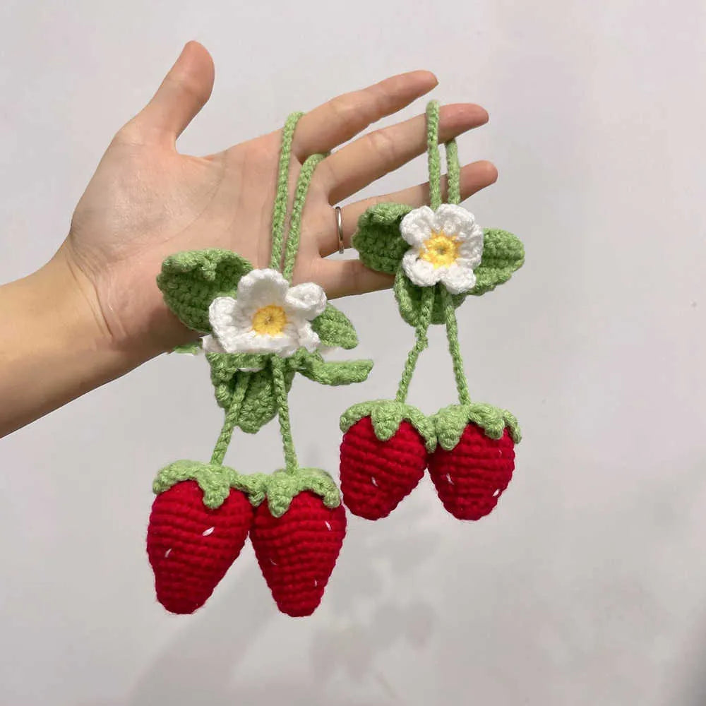 Handmade strawberry-shaped car pendant woven from cotton and hemp wool, hanging as a decorative accessory.