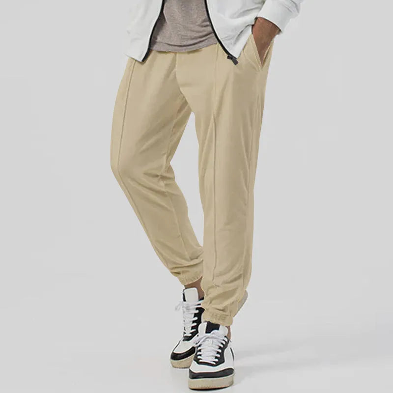 Man wearing grey straight-leg tapered casual sweatpants with an elasticated mid-waist.