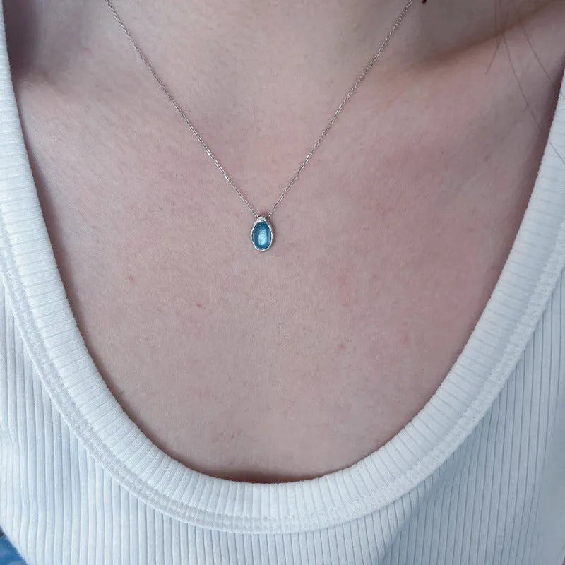 Geometric navy blue and platinum water drop pendant necklace on an adjustable copper cross chain.