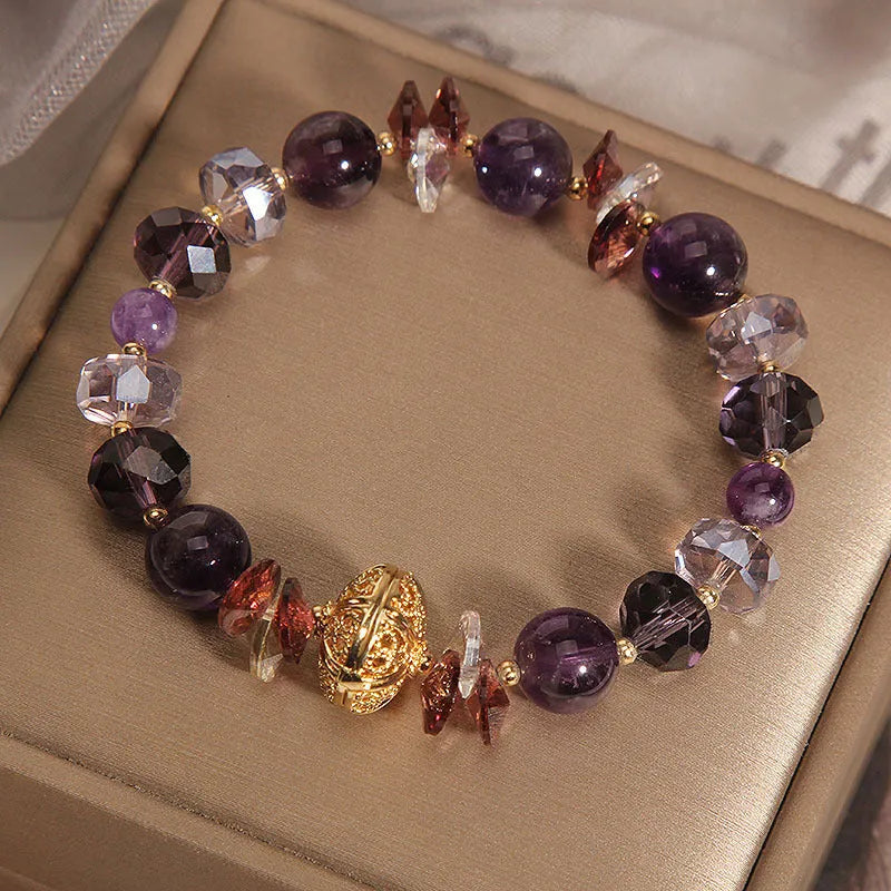 Purple crystal bracelet with pumpkin beads and a wind chimes charm on wrist.